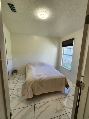Large-format stone-style tile flooring, dual-pane window, and flush-mount ceiling lighting
