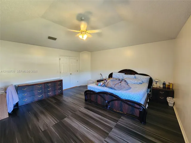 Vaulted ceiling featuring a central multi-blade ceiling fan and wood-finish flooring throughout
