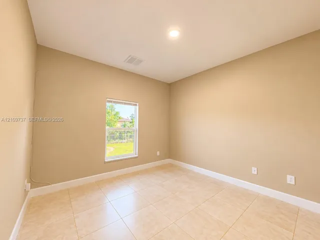 Neutral-toned room featuring large-format ceramic tile flooring, a recessed ceiling light, and a single-pane window