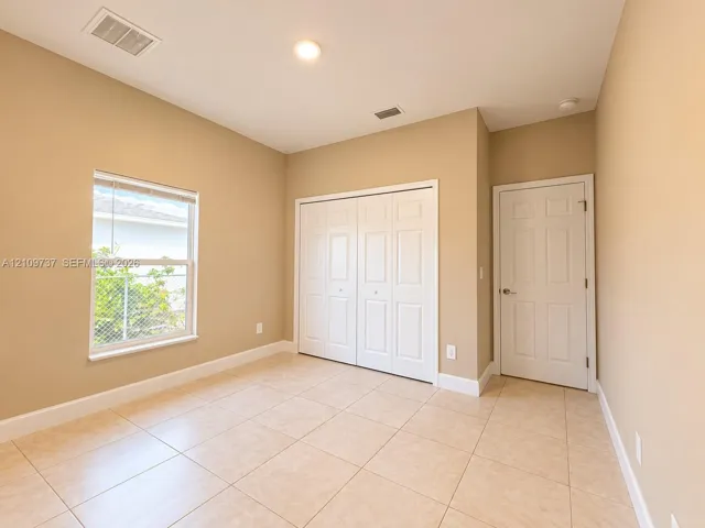 Neutral-toned interior featuring tiled flooring, a single-hung window, bi-fold closet doors, and a six-panel interior door