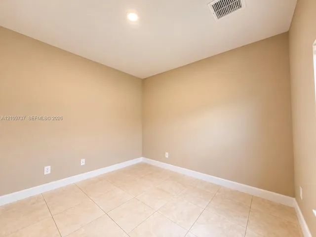 Neutral-toned walls featuring large-format ceramic tile flooring and recessed ceiling lighting