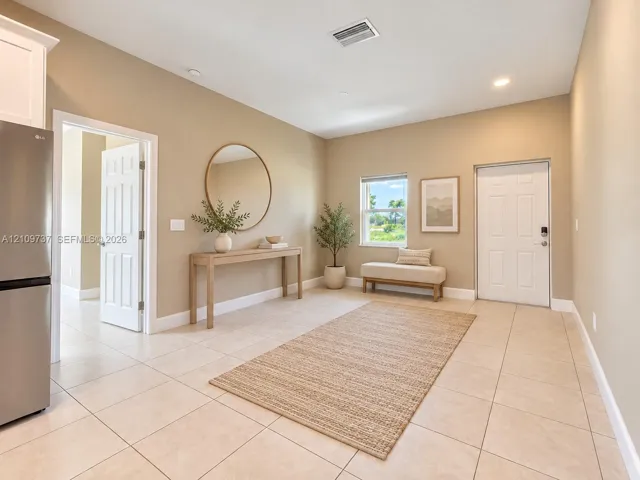 Neutral-toned interior space featuring light tile flooring, recessed lighting, and a six-panel exterior door