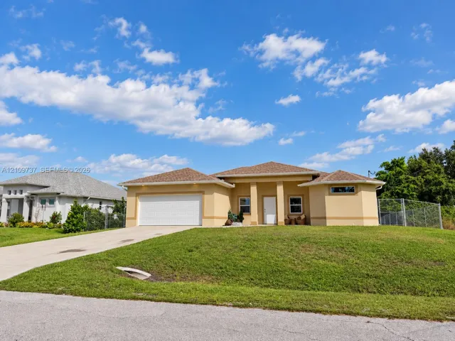 Stucco exterior featuring a multi-hipped roof, covered entryway, double-car garage, and manicured lawn