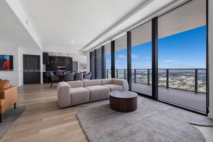 Floor-to-ceiling glass windows, expansive private balcony, wood-finish flooring, and integrated cabinetry