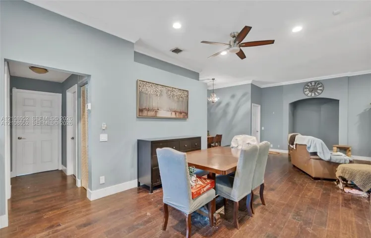 Open-concept interior featuring wood-finish flooring, recessed lighting, crown molding, a ceiling fan, and a recessed arched wall niche