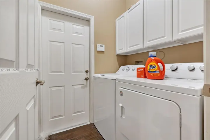 Utility space featuring white shaker-style cabinetry, wood-finish flooring, and a six-panel interior door