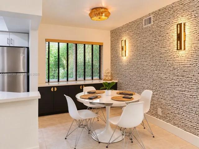 Dining area featuring a statement textured accent wall, built-in cabinetry with metallic hardware, dual wall-mounted light fixtures, and a flush-mount overhead light