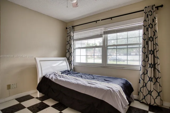 Room featuring grid-patterned tile flooring and horizontal window blinds set within a double-pane window frame