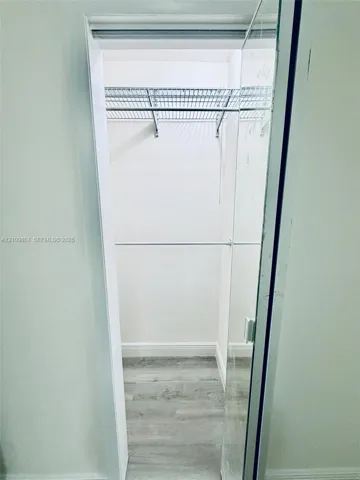 Interior storage space featuring a wire shelving system, integrated clothing rod, and wood-finish flooring
