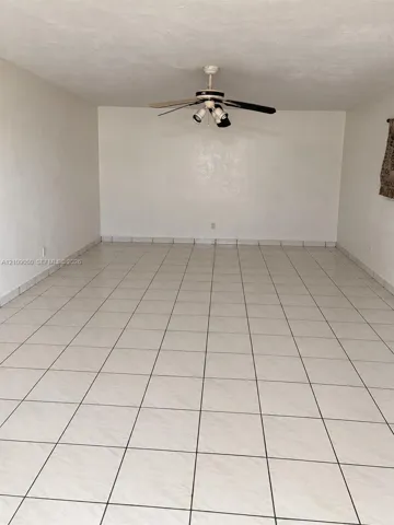 Neutral interior room featuring large-format ceramic tile flooring and a ceiling-mounted fan with integrated lighting