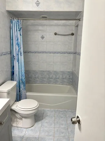 Bathroom featuring a built-in tub with ceramic tile surround, integrated grab bar, decorative tile accents, and tiled flooring