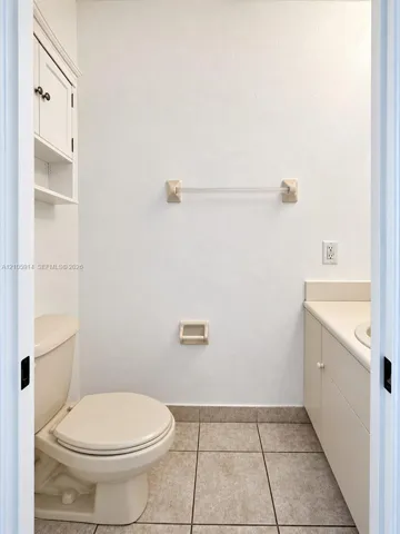 Neutral-toned bathroom featuring tile flooring, built-in cabinetry with a vanity countertop, and wall-mounted storage shelving
