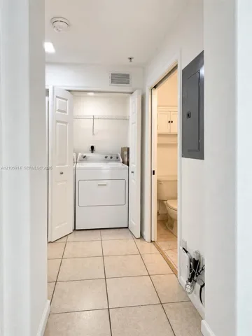 Laundry area featuring tile flooring, built-in wire shelving, and bi-fold closet doors
