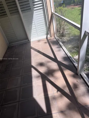 Screened-in patio featuring tile flooring and sliding glass doors with built-in shutters