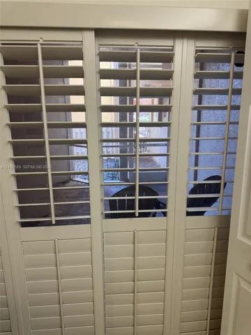 Custom off-white plantation shutters featuring adjustable louvers and integrated center tilt rods