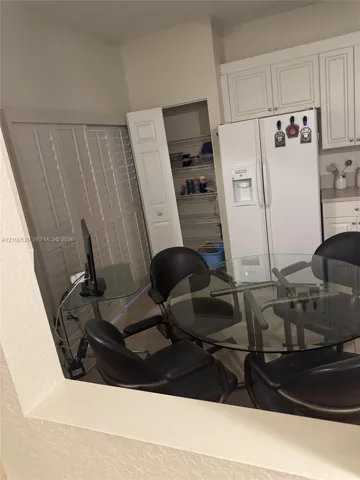 Kitchen featuring white cabinetry, a built-in pantry with wire shelving, plantation shutters, and a side-by-side refrigerator