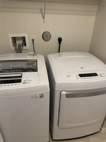 Dedicated laundry area equipped with top-load washer, front-load dryer, recessed water supply box, and overhead wire shelving