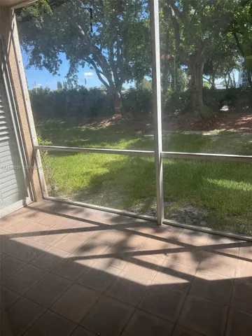 Screened-in porch featuring tiled flooring and exterior access to a backyard with mature trees