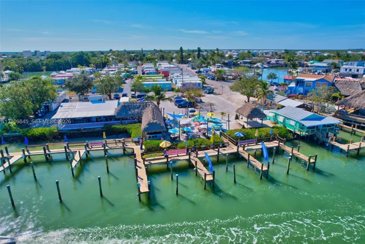 Waterfront property featuring multiple wooden boat docks, thatched-roof structures, and direct water access