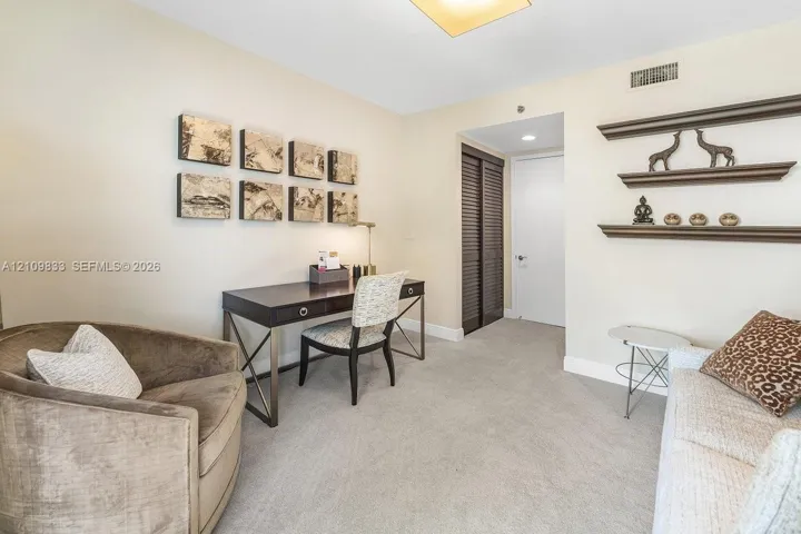 Room featuring neutral wall tones, wall-to-wall carpeting, recessed lighting, built-in wooden shelving, and a closet with louvered doors