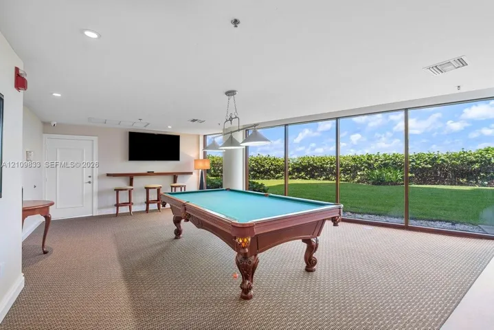 Interior room featuring floor-to-ceiling windows, wall-to-wall carpeting, recessed lighting, and a built-in wooden bar shelf