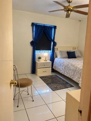 Interior room featuring ceramic tile flooring, a window with horizontal blinds, and a brass-tone ceiling fan