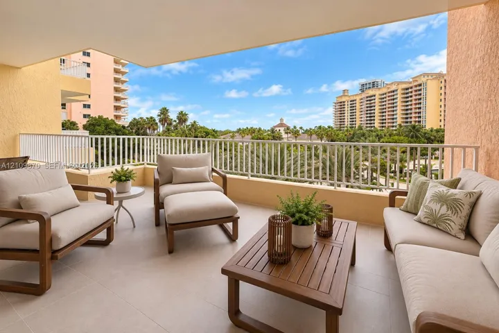 Covered balcony featuring neutral tile flooring, textured stucco walls, and a white metal safety railing