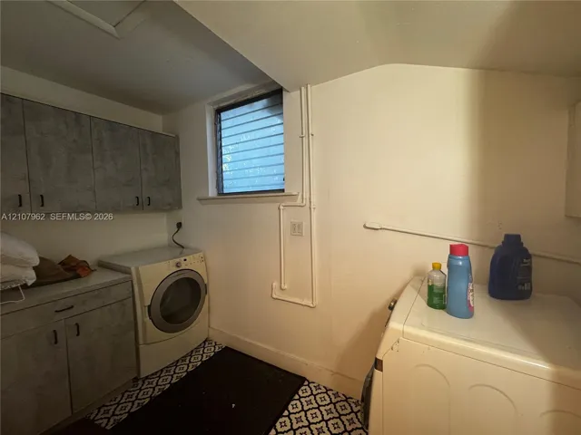 Laundry area featuring built-in cabinetry with stone-finish surfaces and a window with horizontal security bars