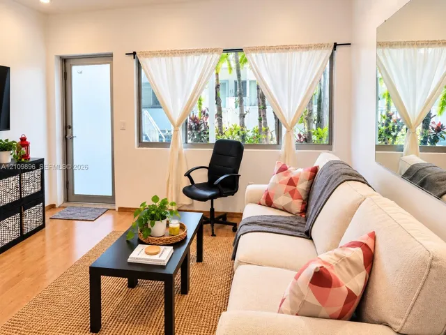 Living area featuring wood-finish flooring, a large wall-mounted mirror, and a glass-paneled exterior door