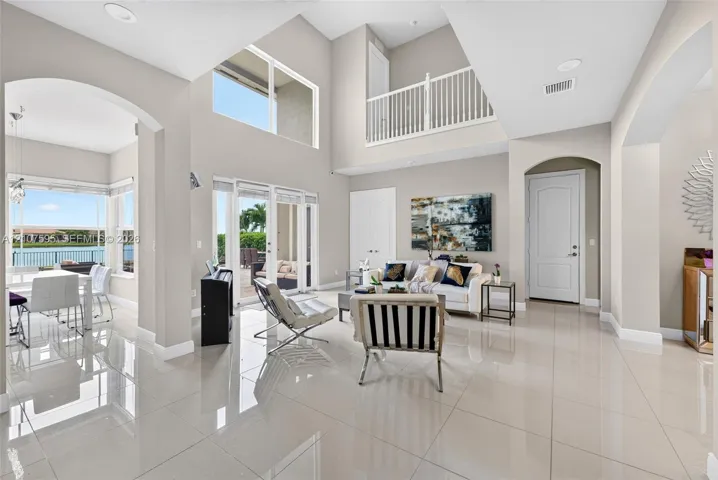 Double-height ceilings, large-format tile flooring, arched architectural detailing, sliding glass doors, and a decorative mezzanine railing