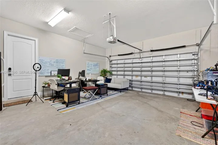 Finished garage featuring a concrete floor, automated overhead door, ceiling-mounted light fixture, and an interior access door