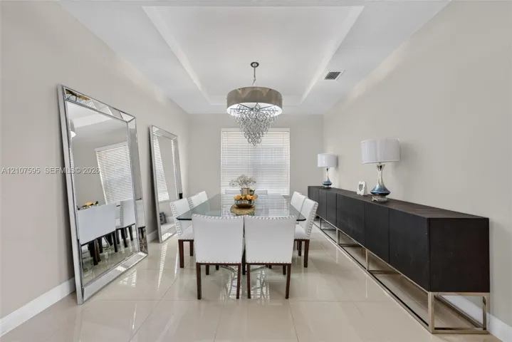 Tray ceiling featuring recessed lighting, polished tile flooring, and a central tiered crystal chandelier