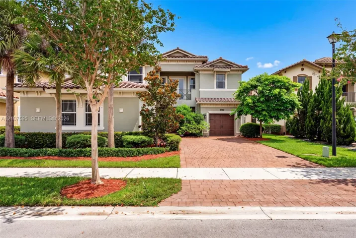Two-story exterior featuring a clay tile roof, stucco finish, paver driveway, and a single-car garage
