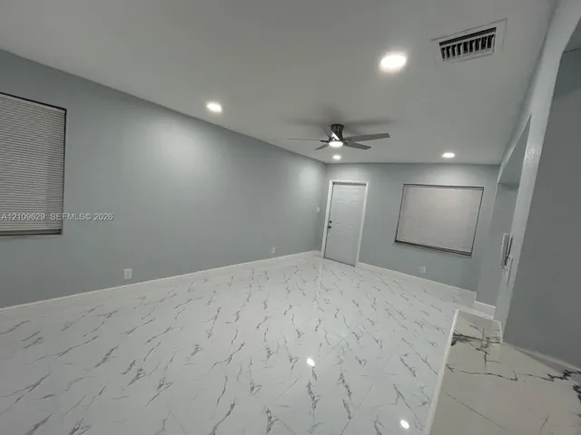 Large-format stone-patterned tile flooring, recessed ceiling lighting, and a multi-speed ceiling fan