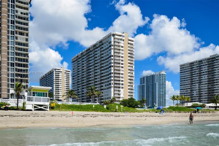High-rise residential buildings featuring white exterior facades, private balconies, and direct access to sandy beachfront