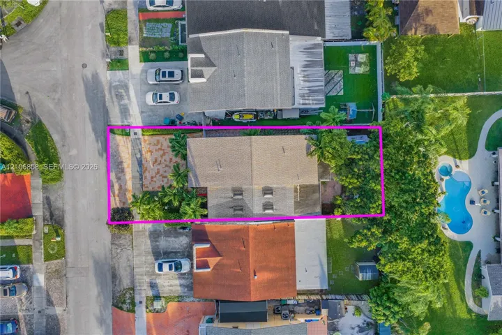 Aerial perspective showcasing a parcel featuring a paved front courtyard, gable roofline, and mature landscaping