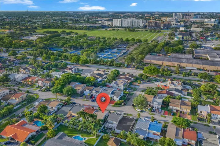 Aerial perspective of a suburban neighborhood featuring a multi-story residential structure, tile roofing, and private outdoor recreational space with a swimming pool