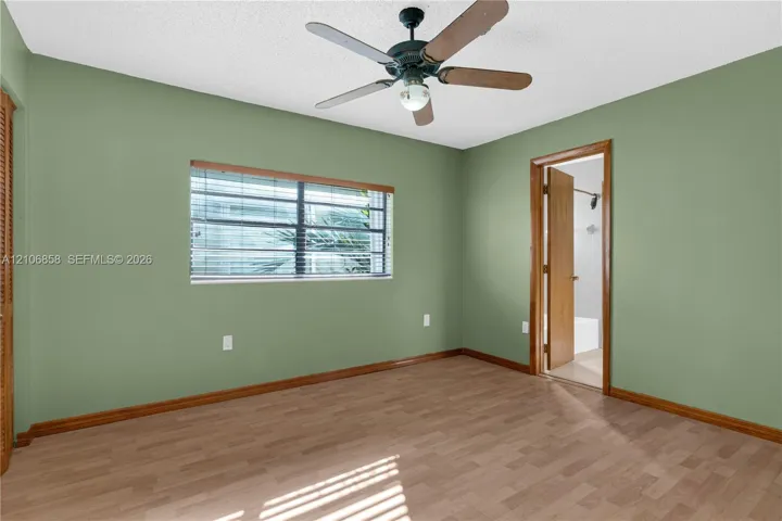 Interior space featuring wood-finish flooring, a multi-blade ceiling fan, and window with integrated blinds