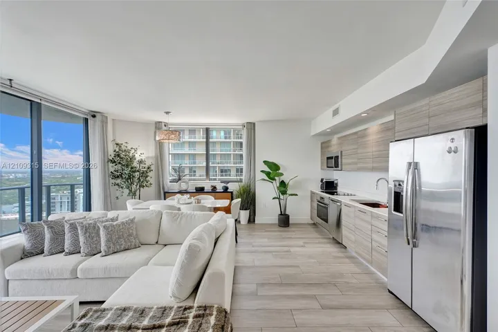Open-concept kitchen featuring horizontal-grain wood-finish cabinetry, stainless steel appliances, and wood-finish tile flooring throughout