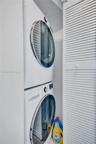 Stacked front-loading washer and dryer set enclosed by white louvered bi-fold doors