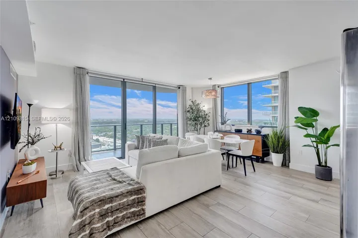 Open-concept living space featuring expansive floor-to-ceiling windows, wood-finish flooring, recessed lighting, and a private balcony