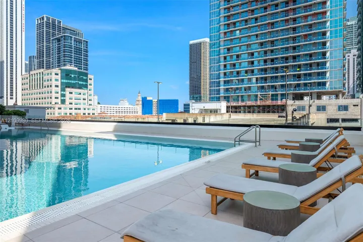 Rooftop swimming pool with a glass-paneled perimeter and light-toned tile decking