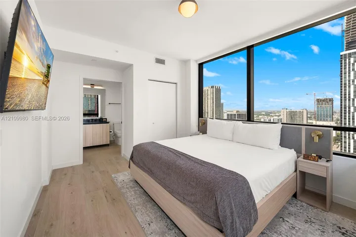 Floor-to-ceiling windows with urban skyline exposure, wood-finish flooring, and minimalist interior finishes