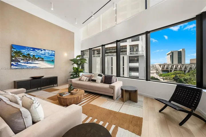Double-height ceilings, floor-to-ceiling windows, wood-finish flooring, and a floor-to-ceiling textured accent wall