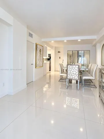 Large-format polished tile flooring, recessed ceiling lighting, and mirrored wall accents