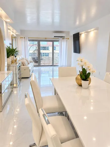 Polished tile flooring, recessed ceiling lighting, wall-mounted air conditioning unit, and glass paneled sliding doors leading to an exterior balcony