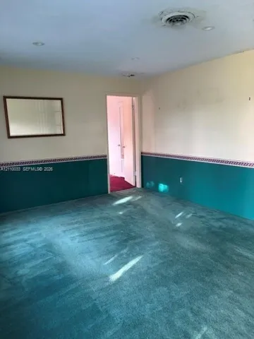 Room featuring full-height walls with decorative wainscoting and inset wall-mounted mirror