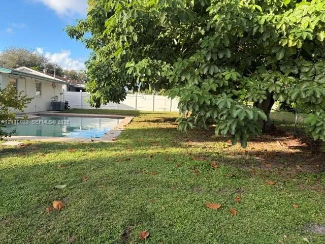 Backyard featuring an in-ground swimming pool, privacy fencing, and established shade trees