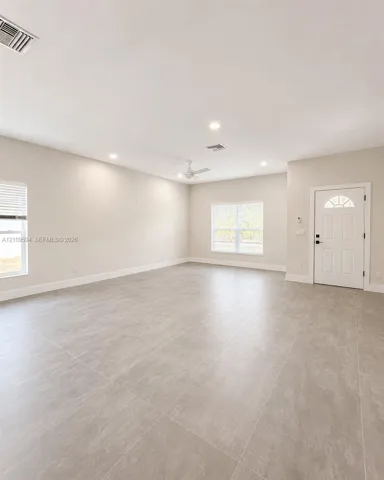 Open-concept interior featuring large-format tile flooring, recessed lighting, a ceiling fan, and windows with integrated blinds