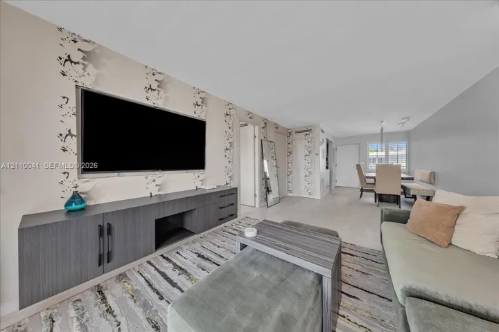 Living area featuring custom charcoal-finish built-in cabinetry, patterned wallpaper, light-toned flooring, and recessed lighting